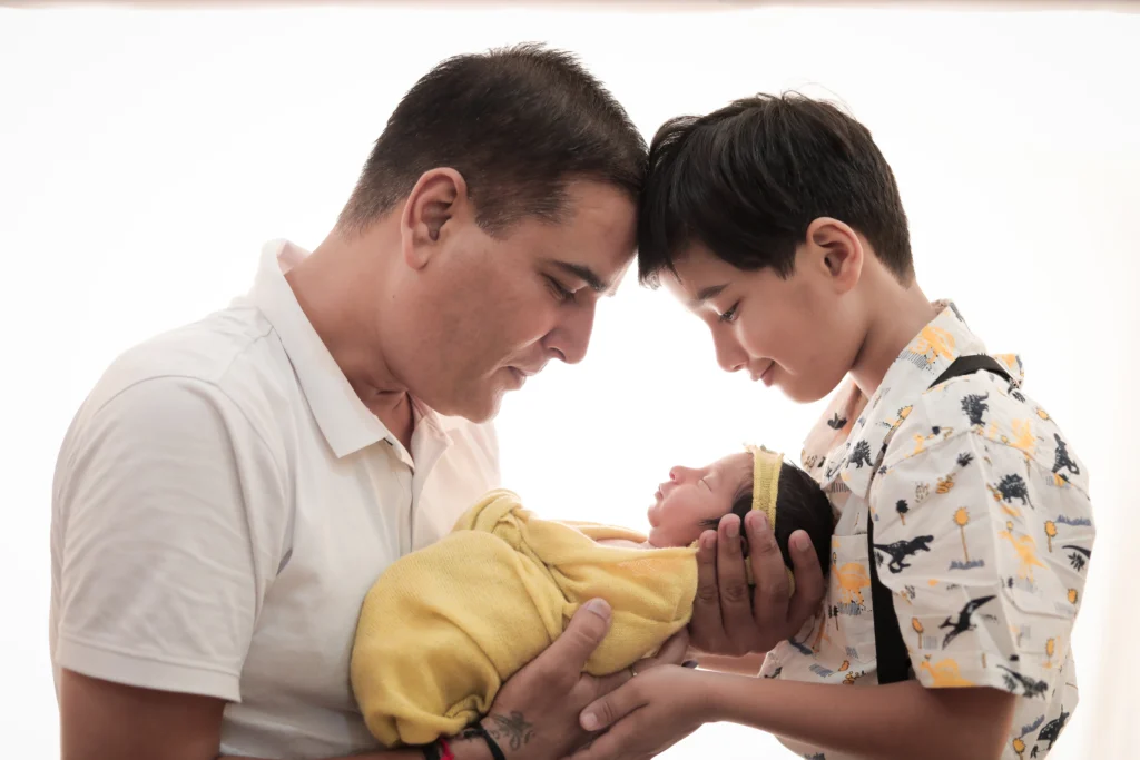 Parents with their baby in a warm-toned frame at a Guwahati photoshoot by ChitraGeek Studios