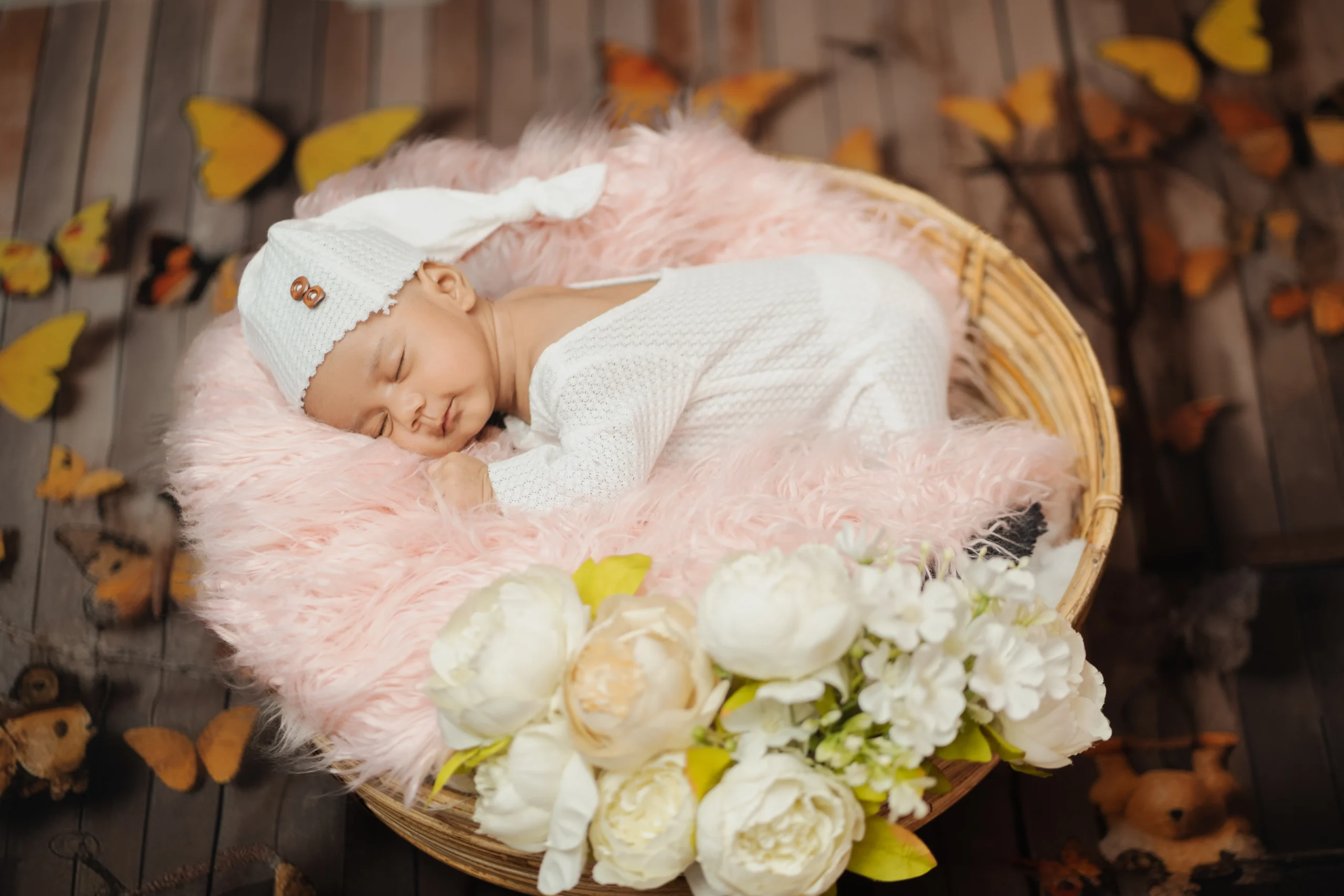 Newborn in a white floral basket setup at a Guwahati baby photoshoot by ChitraGeek Studios