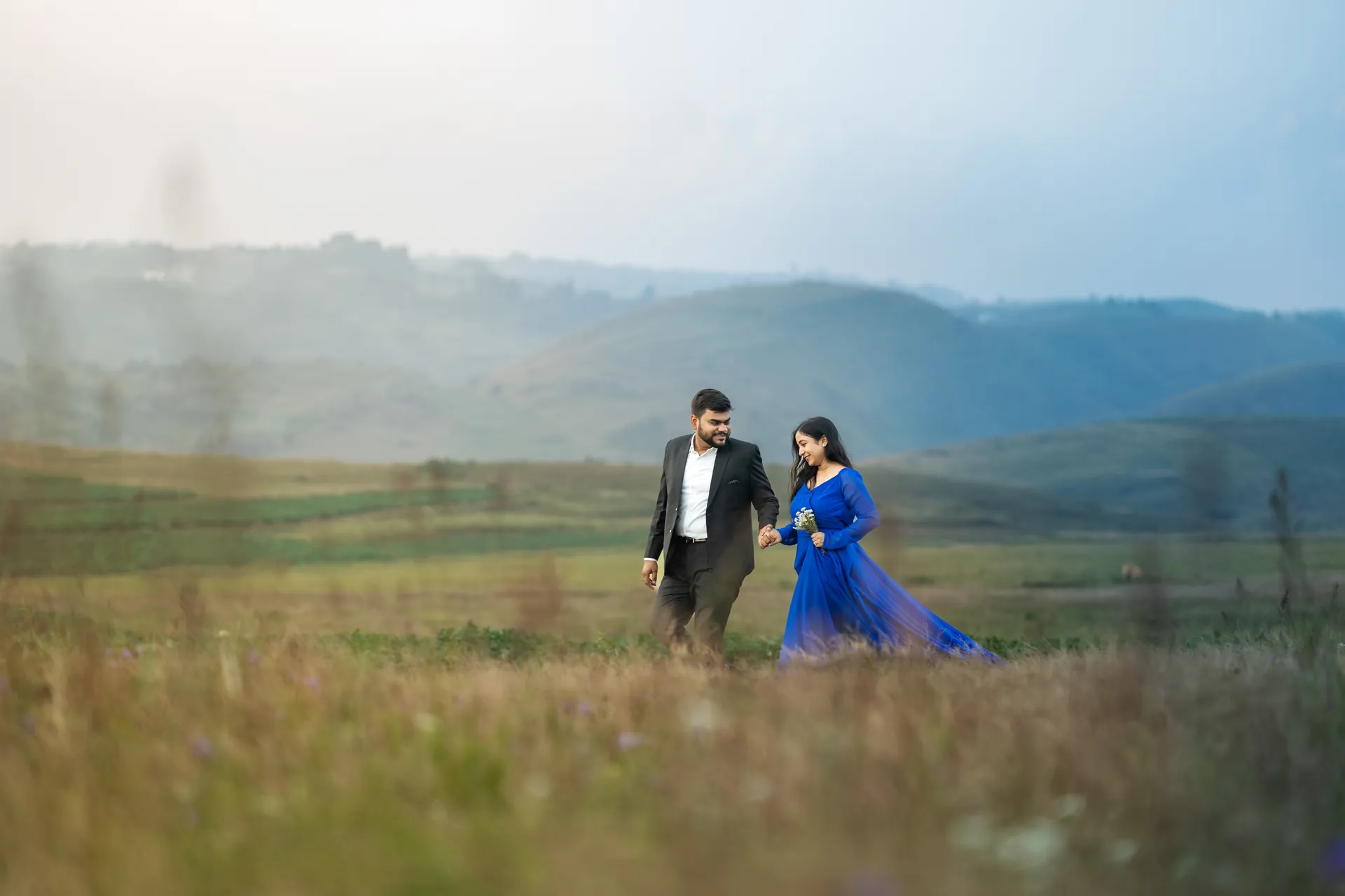 Pre-Wedding Photography in Guwahati by Chitrageek Studios, capturing an intimate couple portrait as they lie together on flowing blue fabric outdoors